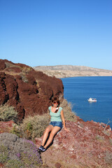 Naklejka premium Portrait of a girl among the red rocks of Santorini