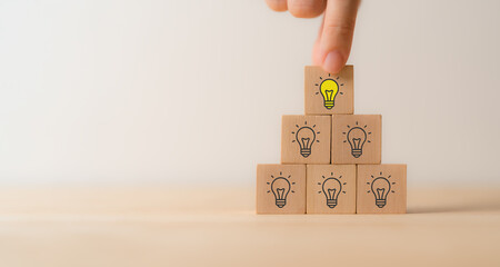 Creative idea, solution and innovation concept. Idea generation and screening for product development process. Wooden blocks with light bulb and yellow color icons on clean background and copy space.