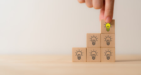 Creative idea, solution and innovation concept. Idea generation and screening for product development process. Wooden blocks with light bulb and yellow color icons on clean background and copy space.