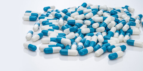 Blue-white antibiotic capsule pills on white background. Pile of antibiotic drug. Antibiotic drug...