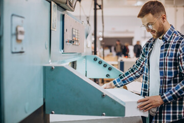 Man working in printing house with paper and paints