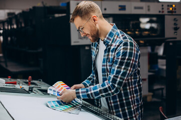 Man working in printing house with paper and paints