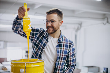 Man working in printing house with paper and paints