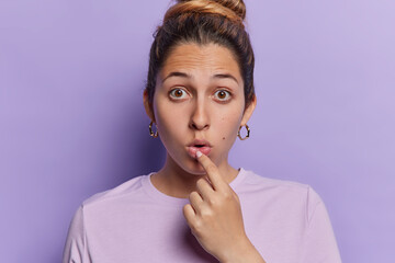 Portrait of shocked lovely woman with combed hair keeps mouth opened has widely opened eyes holds...