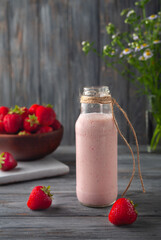 Strawberry smoothie or milkshake in jar on gray wooden background, healthy food for breakfast
