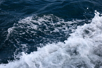 Fototapeta na wymiar Blue sea waves and white foam from the side of the ship.