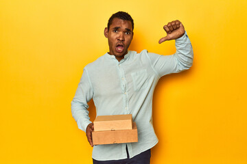African American man with food boxes, yellow studio, feels proud and self confident, example to...