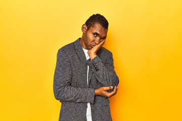 African American man in casual blazer, yellow studio, who is bored, fatigued and need a relax day.