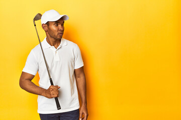 African American golfer in action, posed in a yellow background studio.