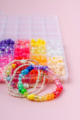 Kids handmade beaded jewelry and different multi-colored beads for children's needlework and crafts in boxes. DIY art activity for kids. Motor skills, creativity and  hobby.