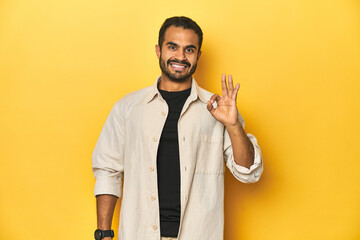 Casual young Latino man against a vibrant yellow studio background, cheerful and confident showing...