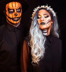 Couple with dark skull makeup on black background. Halloween face art. 