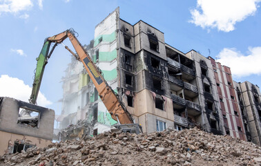 Fototapeta premium Demolition of a high-rise building. The collapse of a residential building. Construction work on the demolition of multi-storey apartments. Excavator with hydraulic crusher.