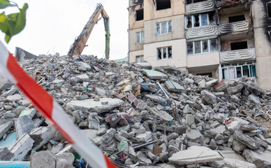 Demolition of a high-rise building. The collapse of a residential building. Construction work on the demolition of high-rise apartments. Fence made of red and white warning tape.