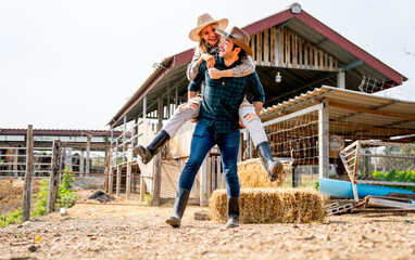 Wide shot of Caucasian man and woman farmer enjoy with woman riding on the back of man and go around the area of their farm with happiness and day light.