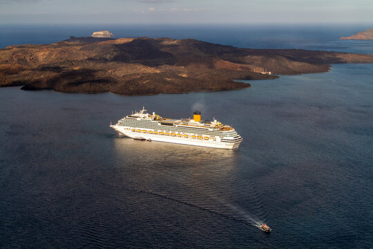 Dawn delights a captivating morning by the anchored cruise ship in Fira's azure bay off the coast of the Greek island Santorini.