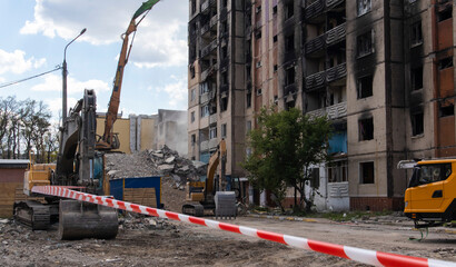Demolition of a high-rise building. The collapse of a residential building. Construction work on the demolition of high-rise apartments. Fence made of red and white warning tape.
