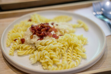 Carbonara fusilli pasta with crispy bacon served on plate