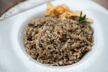 Beef fat fried rice served on plate with rosemary and crispy garlic chips on the background