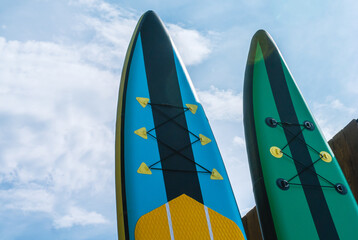 Water sports. Inflatable multicolored sap boards on a background of blue sky. Tourism on sap...