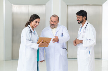 Concentrated male and female doctors in white medical uniforms look at clipboards and discuss patient anamnesis together. team brainstorming make decision concept. - obrazy, fototapety, plakaty