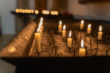 Weiße Kerzen in einer Kirche, Allerheiligen, brennende Kerzen in einer Reihe.