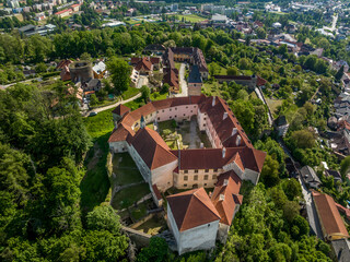 Aerial view of Vimperk Renaissance chateau castle with fortified round gun tower above the medieval town with blue sky