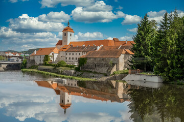 Strakonice medieval castle reflecting off the Otava river with cloudy blue sky background