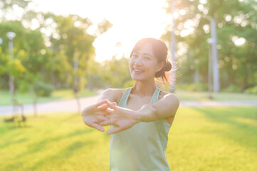 Female jogger. Fit young Asian woman with green sportswear stretching muscle in park before running and enjoying a healthy outdoor. Fitness runner girl in public park. Wellness being concept