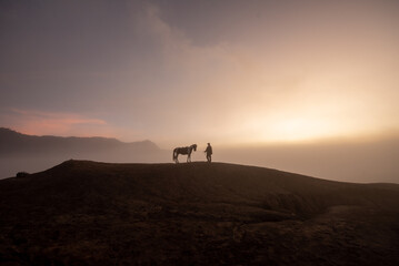 Beautiful sunrise scenery with silhouette horseman and his horse at Bromo Mountain, Bromo Tengger National Park