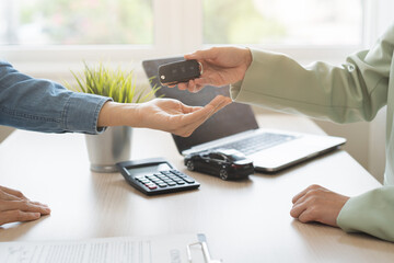 Fototapeta premium Business car rental, sell service, dealership hand of agent dealer, sell asian young woman giving auto key of vehicle to customer renter, female buyer receiving, client or tenant, transfer automobile.
