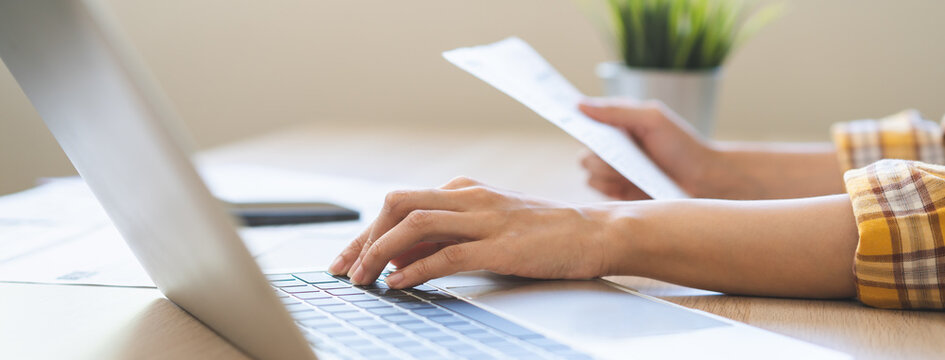 Bill pay concept. Online internet banking asian young woman work at desk on laptop computer at home, female calculate finance, hand holding paperwork, bills tax for payment. Technology of financial.
