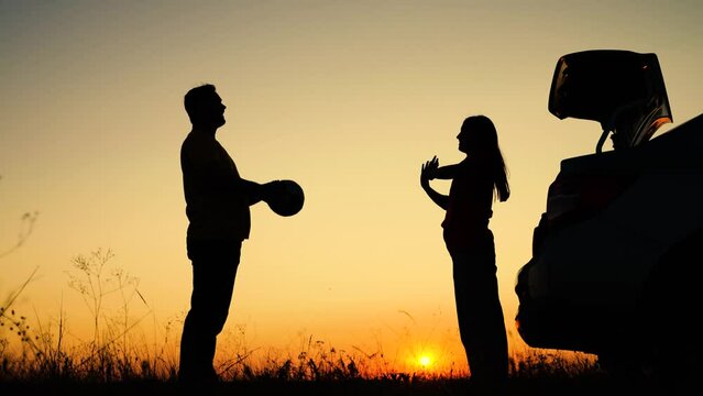 Happy family travels by car. Travelling by car. Family holiday child. Parents and children stopped at camping by car. Dad with child, daughter on his shoulders, mom, children play with ball, sunset.