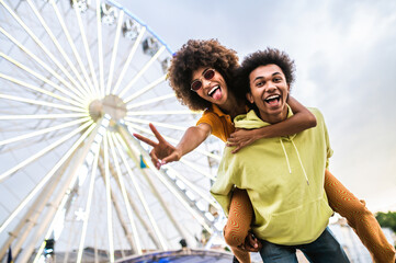 Multiracial young couple of lovers dating at theferry wheel in the amusement park - People with...