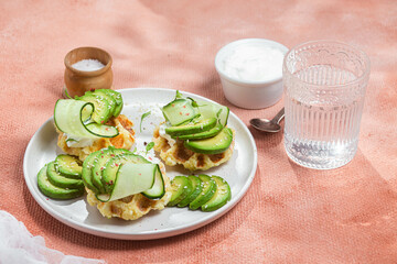 Waffles with cream cheese, avocado and cucumber on a plate