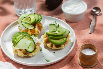 Waffles with cream cheese, avocado and cucumber on a plate