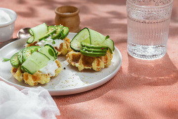 Waffles with cream cheese, avocado and cucumber on a plate