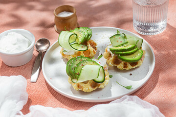 Waffles with cream cheese, avocado and cucumber on a plate