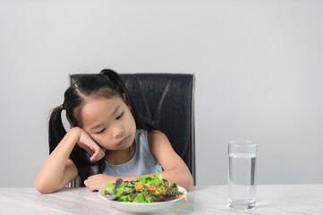 Little asian cute girl refuses to eat healthy vegetables.Nutrition & healthy eating habits for kids...