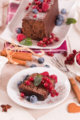 Chocolate sponge cake with fresh fruit on white dish. - 616769416
