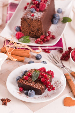 Chocolate sponge cake with fresh fruit on white dish.