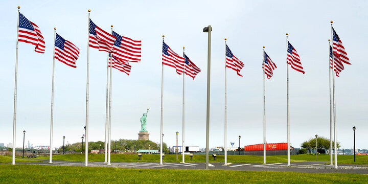 a view of Manhattan city skyline staue of liberty also visible from battery park , American flags in battery park, new jersey, USA 