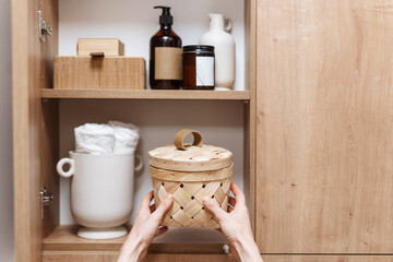 Obraz na płótnie Canvas woman take storage box with hygiene products from cupboard