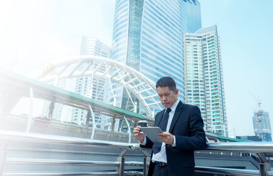 Businessman drinking cup of coffee while reading information for stock market investment