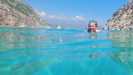 The girl's head is above the surface of the water. She has a diving mask on her head. The woman is smiling broadly. The concept of a summer holiday. Slow motion