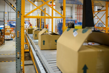 conveyor belt in the delivery warehouse, with packing cartons in the foreground