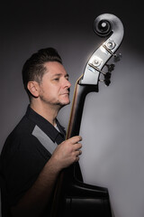 Vertical studio portrait of a 40 years old male artist with his double bass rockabilly style
