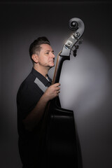 Vertical studio portrait of a 40 years old male artist with his double bass rockabilly style