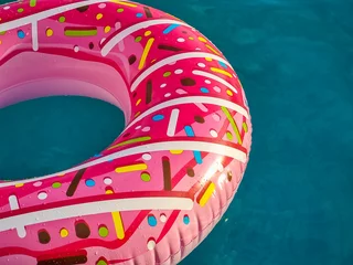 Selbstklebende Fototapeten bright pink inflatable ring floating in swimming pool. Vacation concept with copy space © Yulia