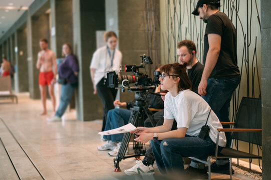 The director is a woman at work on the set. The director works with a group or with a playback while filming a movie